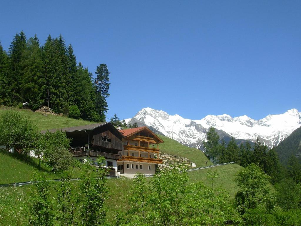 a house on a hill with mountains in the background at Ausserangistlhof in Campo Tures