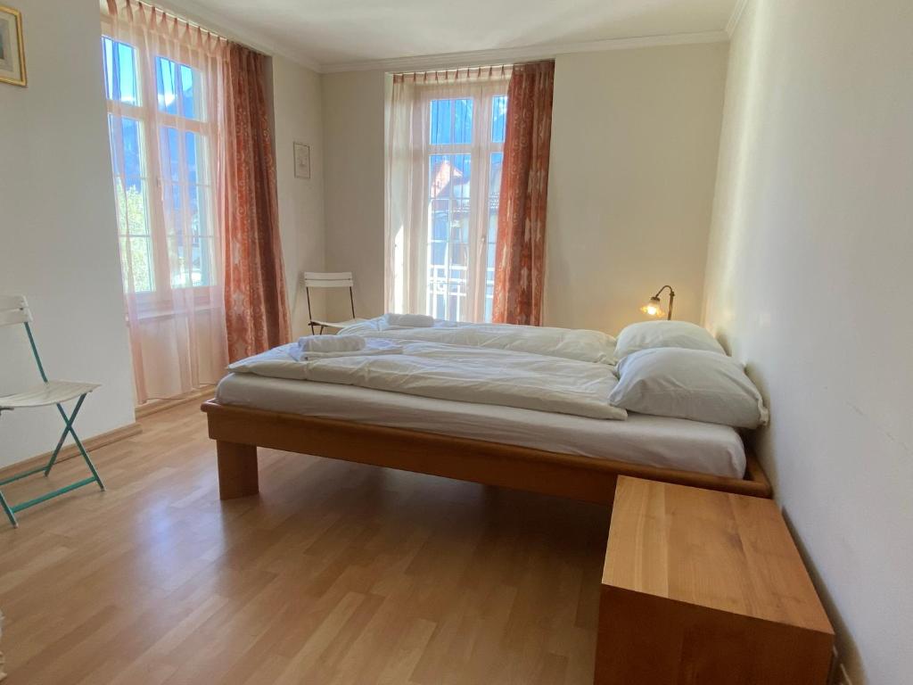 a large bed in a room with two windows at Bad Ragaz Appartement in Bad Ragaz