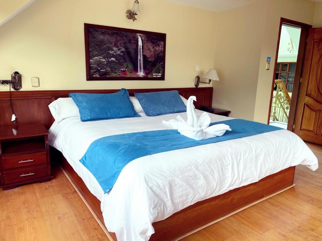 a bedroom with a large bed with a white bird on it at Hotel Donde Marcelo in Baños