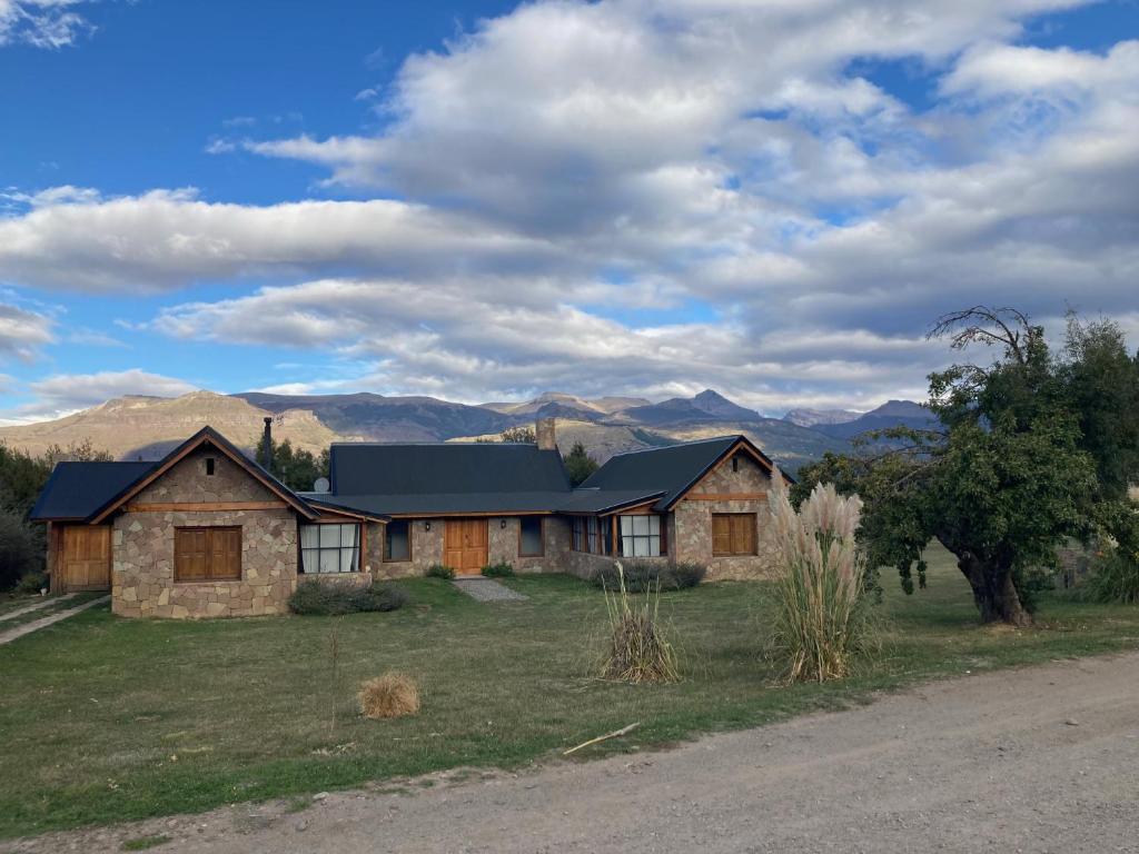 una casa en un campo con montañas en el fondo en Casa Rincon Radales en San Martín de los Andes