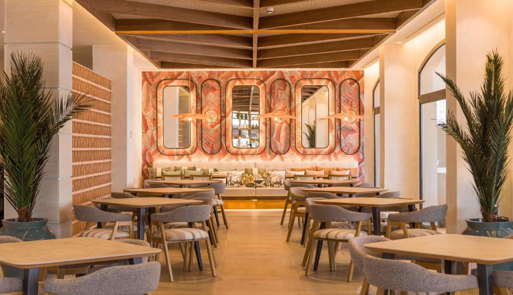 a restaurant with tables and chairs and a mural at Ilunion Islantilla in Islantilla