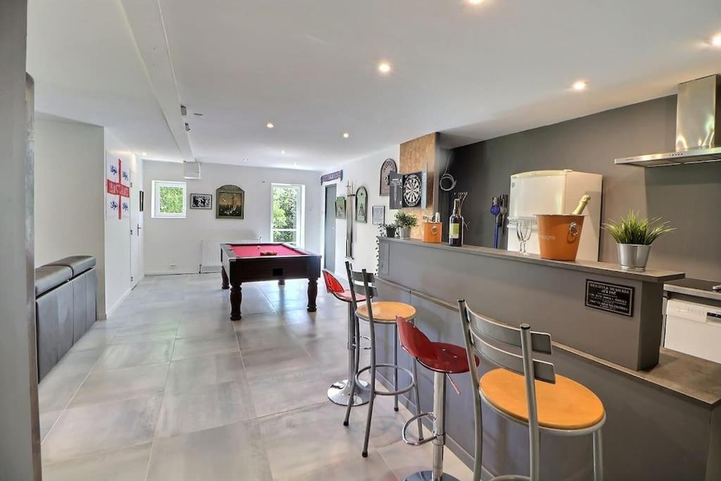 eine Küche mit zwei Hockern und einer Theke mit einem Tisch in der Unterkunft maison moderne en pleine nature, avec spa de luxe in Maringes