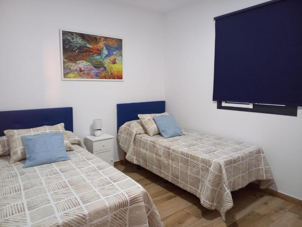 a bedroom with two beds and a painting on the wall at Casa Rosalinda in Conil de la Frontera