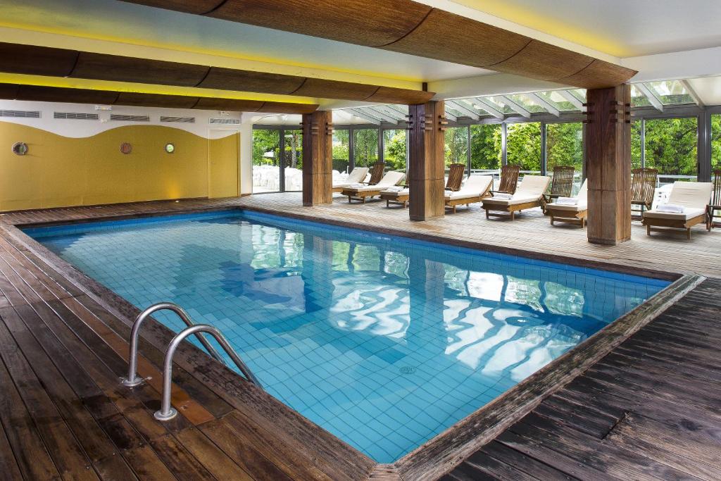 - une piscine dans un hôtel avec des chaises et des tables dans l'établissement Family Hotel, à Vic-sur-Cère