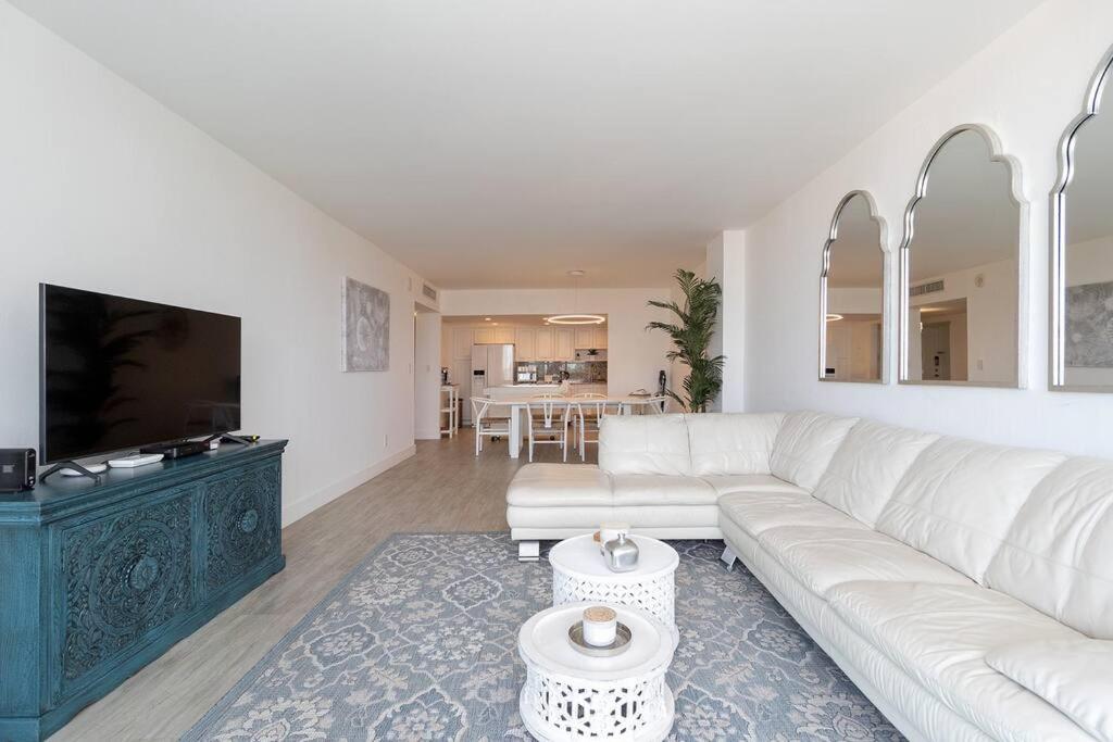 uma sala de estar com um sofá branco e uma televisão em Stunning & Spacious Resort-Style Condo Across From Beach! em Miami Beach
