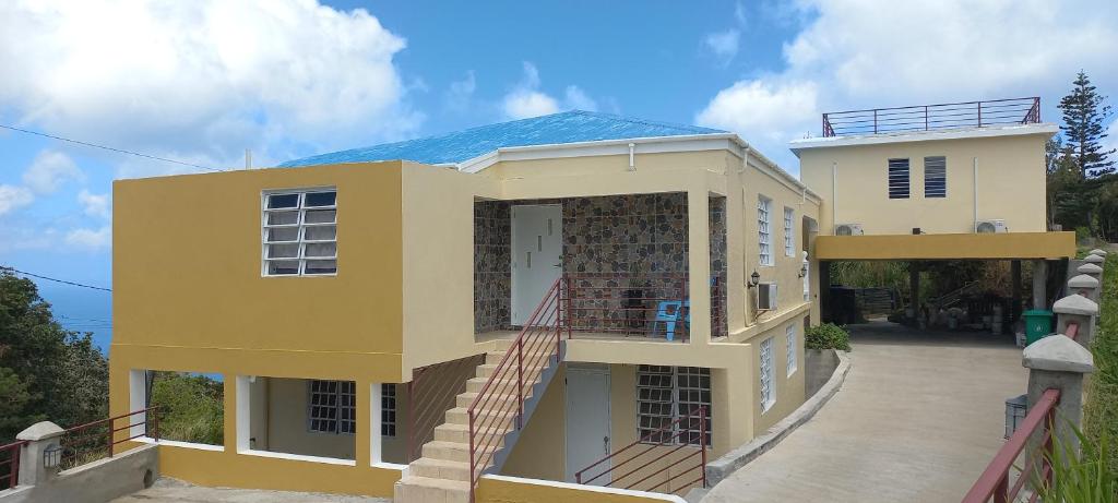 a yellow house with a staircase in front of it at More Than Beauty Properties in Tortola Island