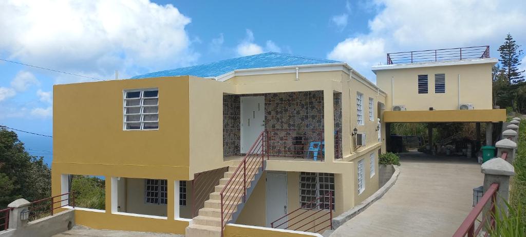 una casa amarilla con una escalera delante de ella en More Than Beauty Properties, en Tortola Island