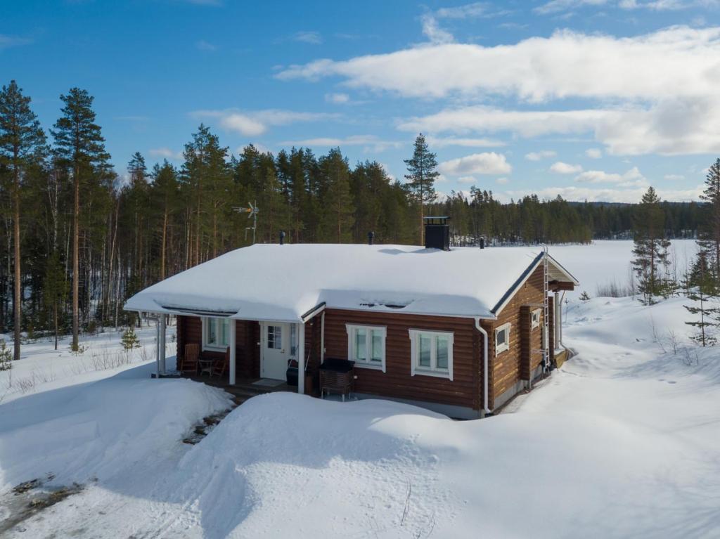a cabin with snow on the roof in the woods at Luxury Villa Rahavaara in Joensuu