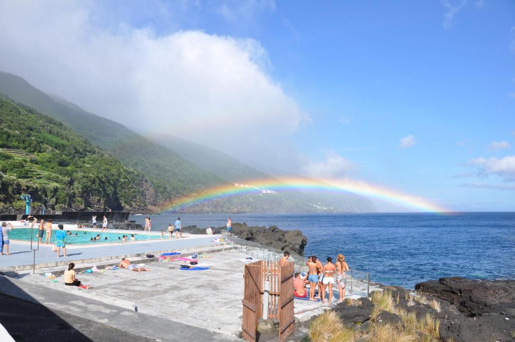 un gruppo di persone in una piscina con un arcobaleno di Casa da Abrótea a Lajes do Pico