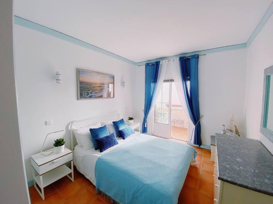1 dormitorio con cama con sábanas azules y ventana en Beach House Casa Dolce in Benagil, en Benagil