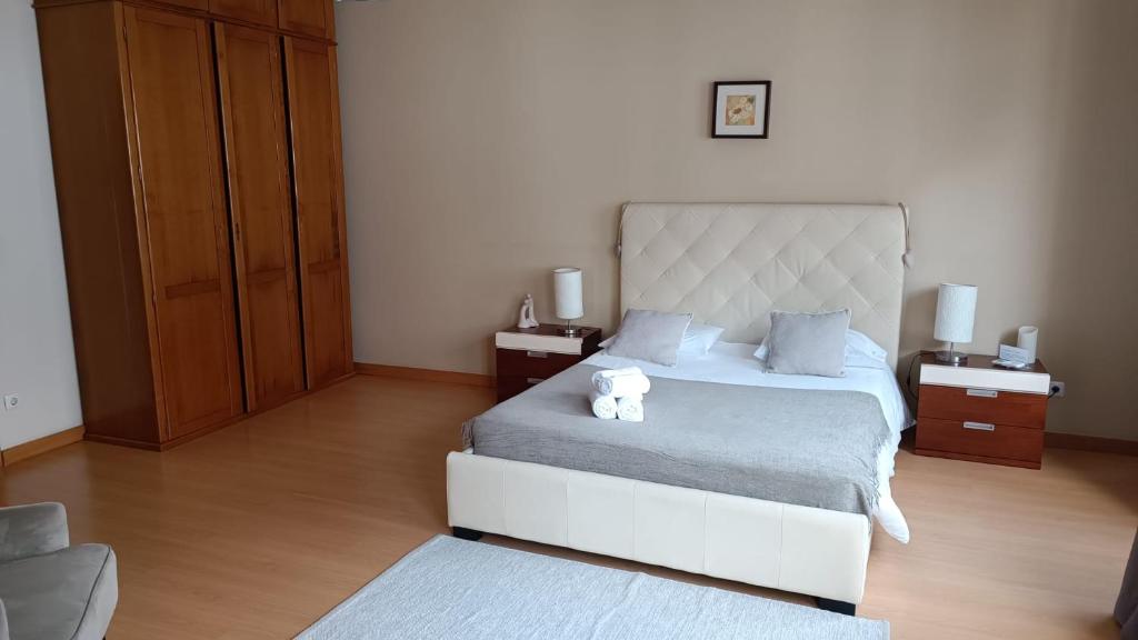 Apartamento Pérola da Vila في فيلا فرانكا دو كامبو: غرفة نوم بسرير كبير وموقف ليلتين