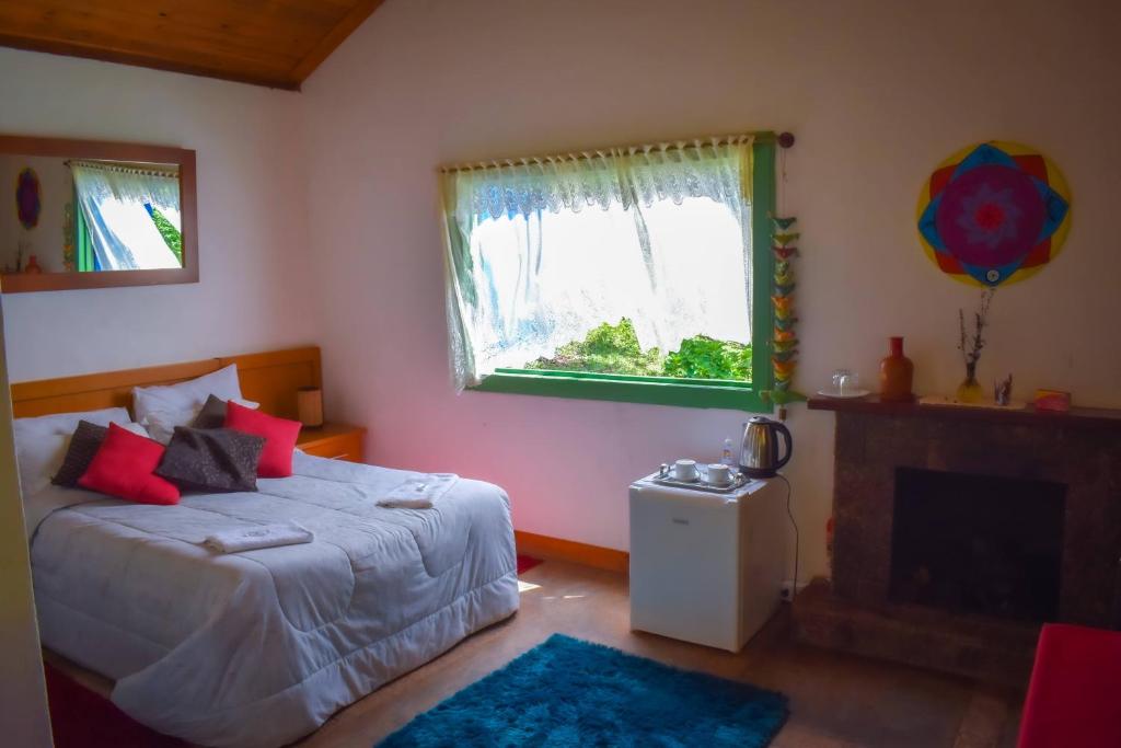 1 dormitorio con 1 cama, chimenea y ventana en Hotel Fazenda Boa Esperança en Delfim Moreira