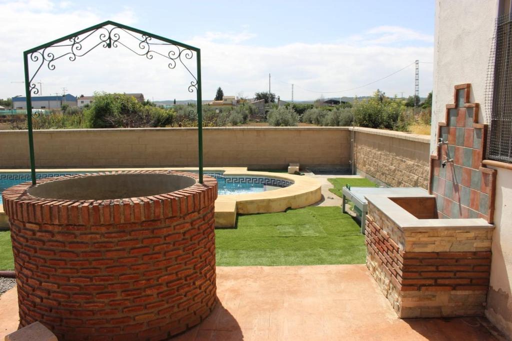 un patio trasero con una hoguera de ladrillo y una piscina en CORTIJO HOYA MESA, en Santa Fe