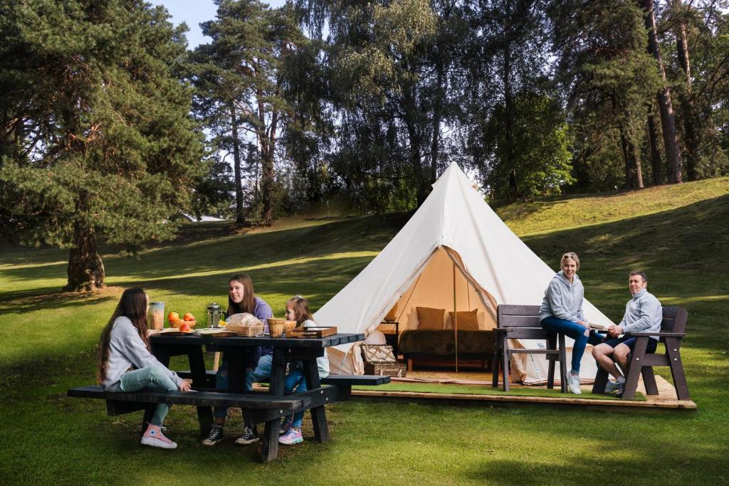 een groep mensen die aan picknicktafels voor een tent zitten bij Westport Estate Glamping Village in Westport
