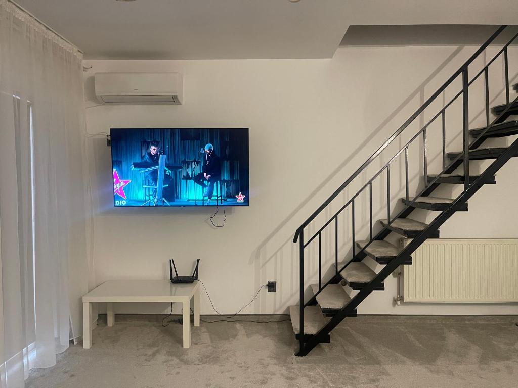 Habitación con escalera y TV en la pared. en Apartament cu scara interioară, en Floreşti