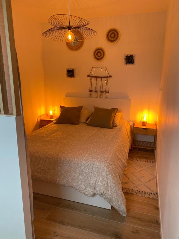 a bedroom with a bed with two lights on it at Escapade Normande avec son sauna privé in Le Tourneur