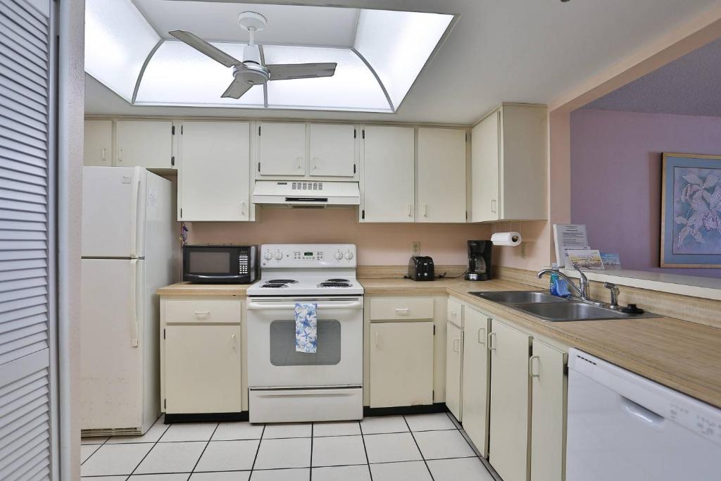 cocina con electrodomésticos blancos y ventilador de techo en 305 - Kima, en St Pete Beach