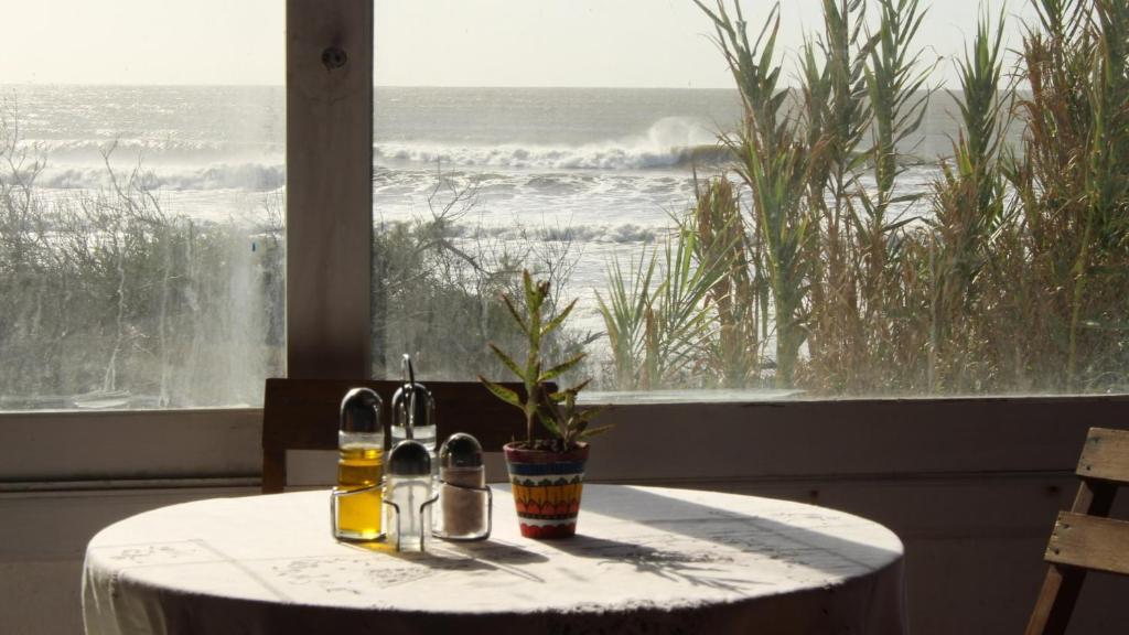una mesa con vistas al océano desde una ventana en Guesthouse Entre Campo y Mar, en La Coronilla
