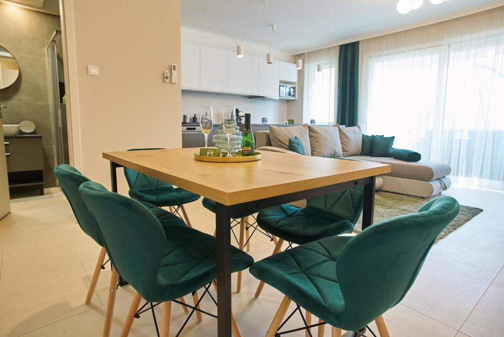 a dining room table with green chairs in a living room at Sunlight Green - Szeged in Szeged