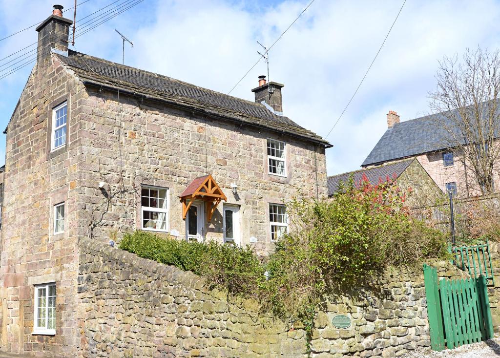 una antigua casa de piedra con una pared de piedra en Gate Cottage, en Matlock