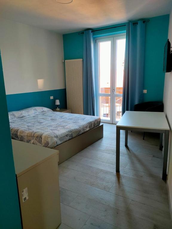 ein Schlafzimmer mit einem Bett, einem Fenster und einem Tisch in der Unterkunft CARrooms in Carrù