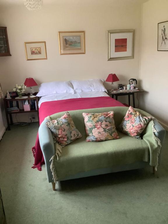 a bedroom with a bed with a green couch with pillows at Garwood House in Holt
