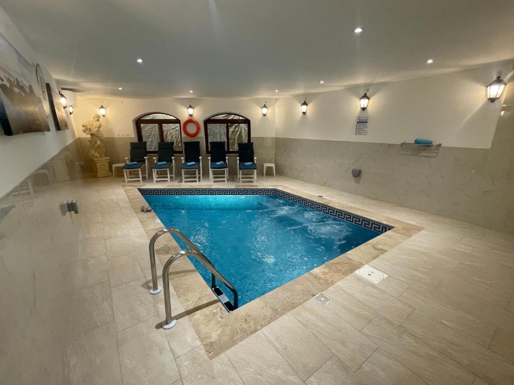 a swimming pool in a building with chairs around it at Alina Boutique Living in Victoria
