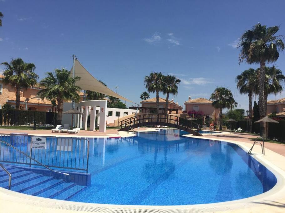 une grande piscine avec un pont et des palmiers dans l'établissement House sleeps 6, large pool walk to beach, à Vera