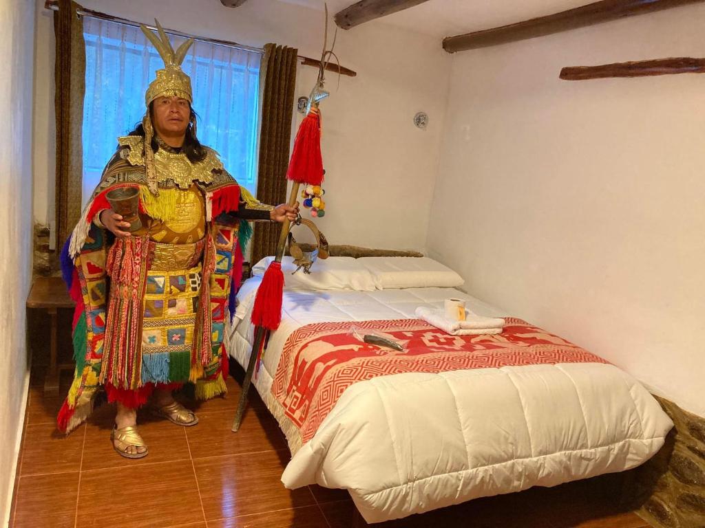 a man standing next to a bed in a room at Mirador inka in Ollantaytambo