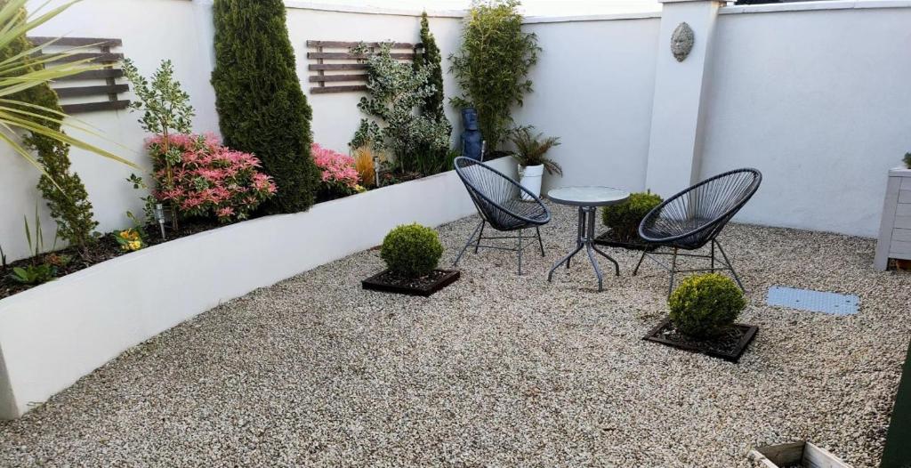 a patio with two chairs and a table and some plants at Russell Mews in Ennis