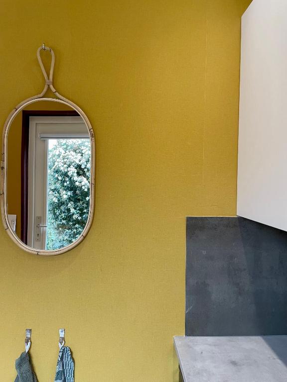 a mirror on a yellow wall in a bathroom at Bed & Breakfast Danina in Sassenheim