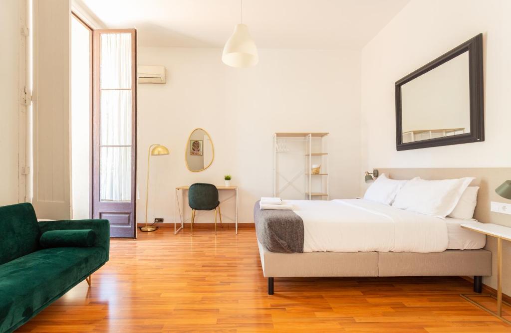 a white bedroom with a bed and a green couch at Casa Lolita in Barcelona