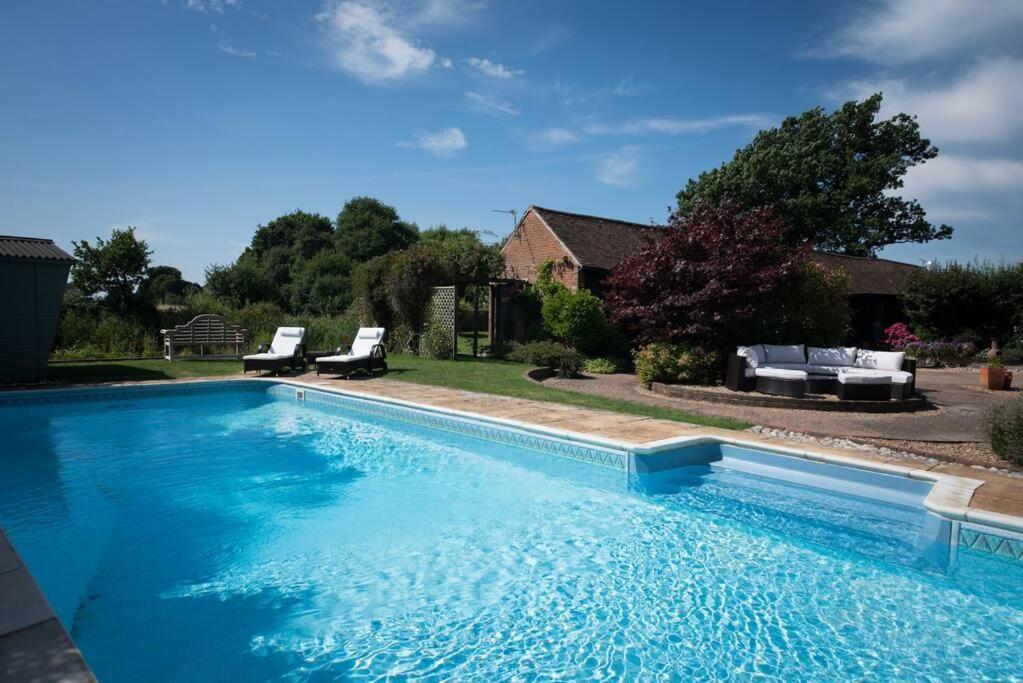 uma grande piscina com duas cadeiras e uma casa em Rural cottage with swimming pool! em High Halden