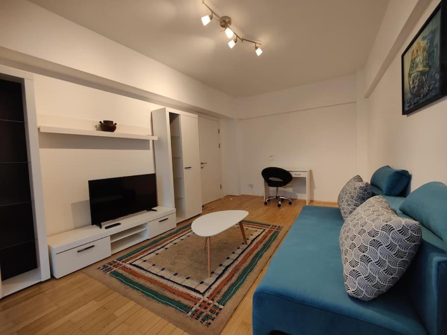 un salon avec un canapé bleu et une télévision dans l'établissement Apartament The Cozy Nest Turda, à Bucarest
