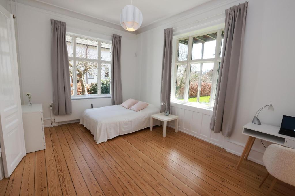 a white bedroom with a bed and two windows at Scandi-Hygge Seaside House - only 10mins to Copenhagen in Charlottenlund