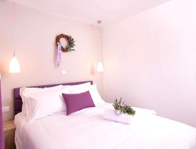 een slaapkamer met een wit bed met een paars hoofdeinde bij Lena Apartments 3 in Potos
