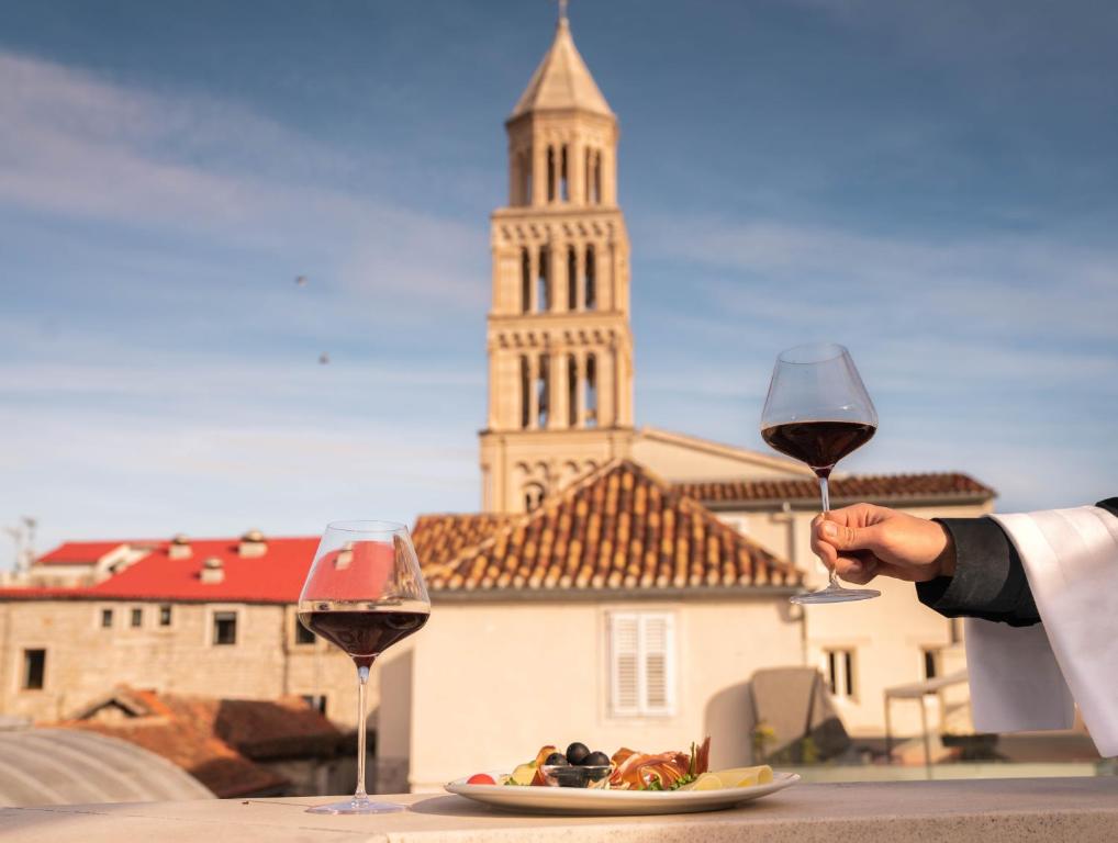 una persona sosteniendo una copa de vino junto a un plato de comida en Slavija Culture Heritage Hotel, en Split