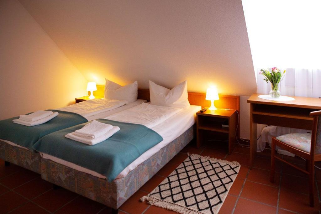 a bedroom with a bed with two lamps and a desk at Hotel Sofra in Fürth