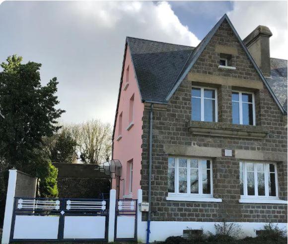 uma casa cor-de-rosa com uma vedação à frente. em maison de village em Chérencé-le-Roussel