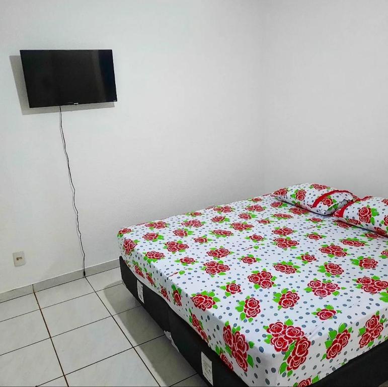 a bedroom with a bed with a floral comforter at POUSADA ROSA BRANCA in Uberlândia