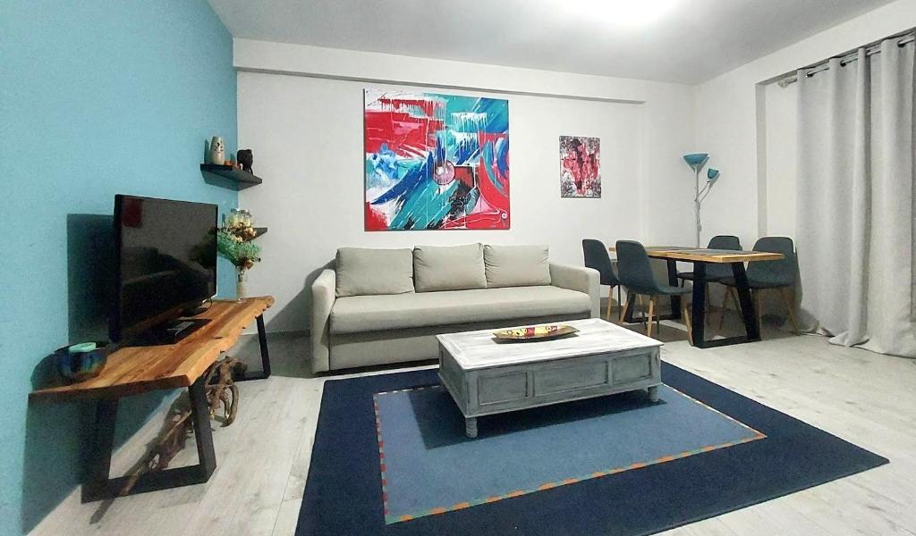 ein Wohnzimmer mit einem Sofa, einem TV und einem Tisch in der Unterkunft Apartment in Ioannina