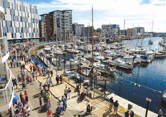 a crowd of people walking around a marina with boats at Waterfront town centre ipswich apartment in Ipswich