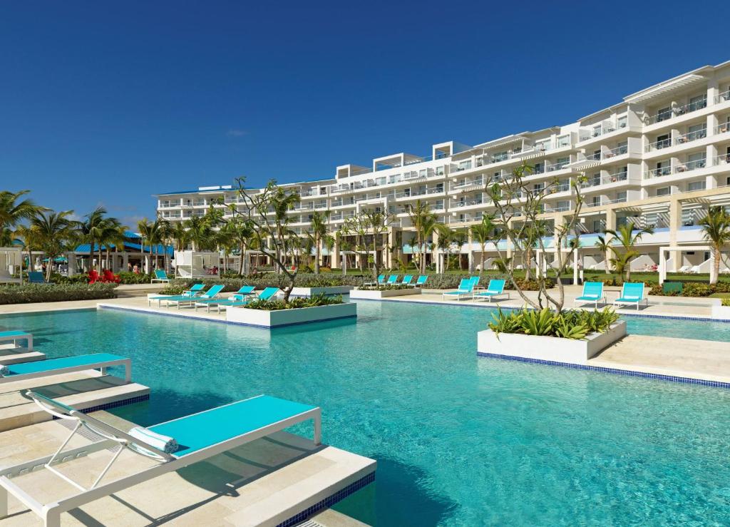 a swimming pool with chairs and a large building at Margaritaville Beach Resort Cap Cana Wave - An All-Inclusive Experience for All in Punta Cana