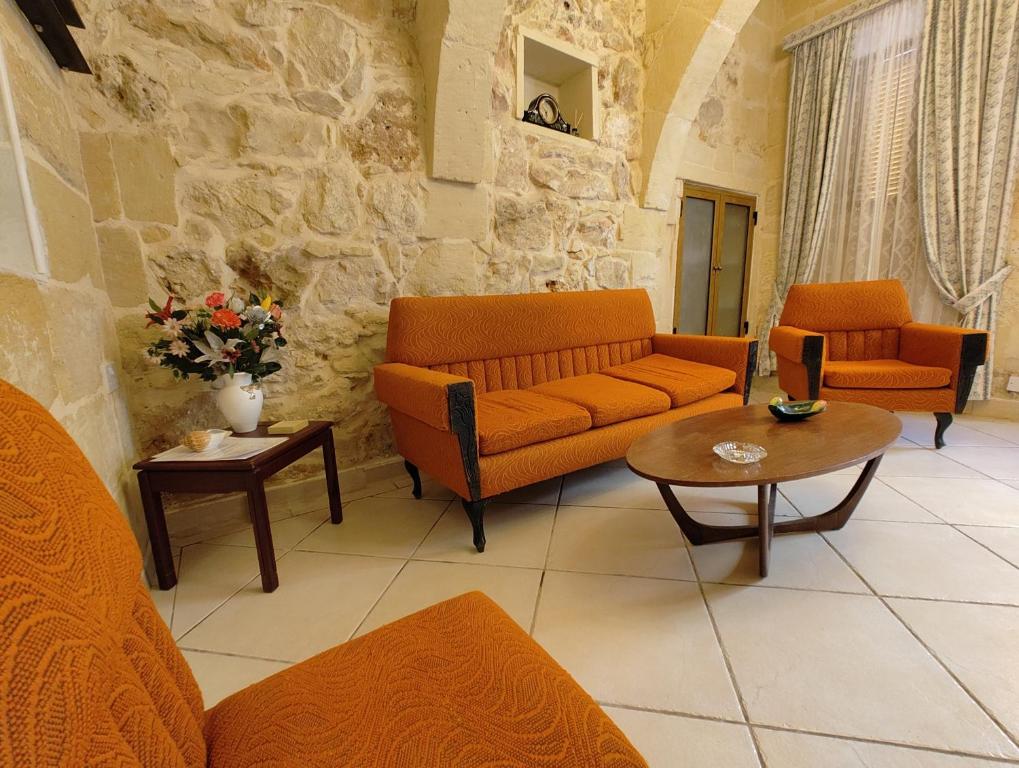 a living room with orange couches and a table at Charming rustic getaway in Xaghra, Gozo. in Xagħra