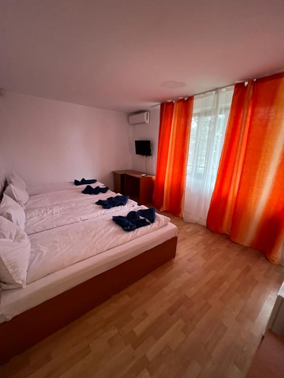 a bedroom with a bed and a window with orange curtains at Hellen Residence in Costinesti