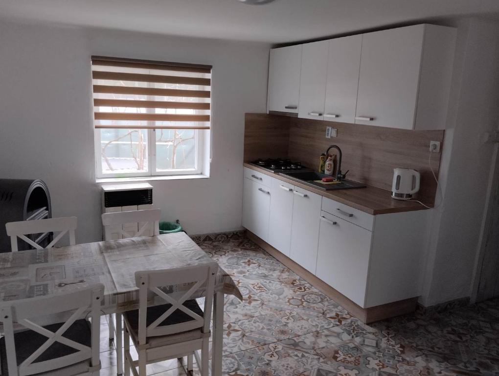 a kitchen with white cabinets and a table with chairs at Ubytovanie Tibor Skarba in Dunajská Streda