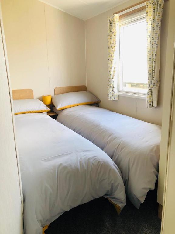 two beds in a small room with a window at Cosy holiday home at Romney Sands in New Romney