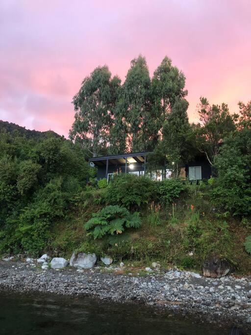 a house sitting on top of a hill next to a river at Casa Lago Rupanco in Puerto Rico