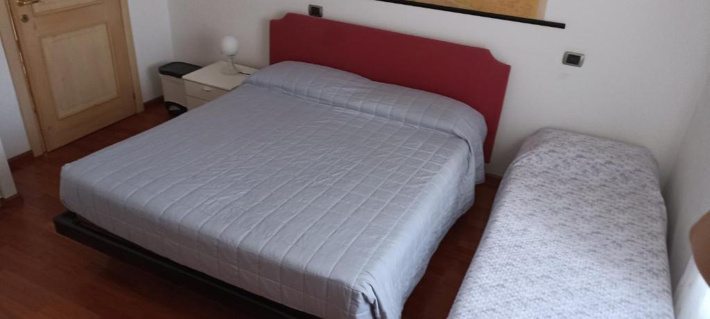 Illegio的住宿－Cjase di Doro，卧室配有白色的床和红色床头板