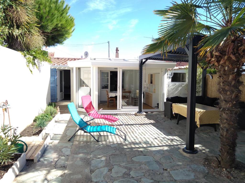 une terrasse avec 2 chaises et une maison dans l'établissement Maison Boisvinet Saint-Gilles-Croix-de-Vie, 4-5 p, belle cour intérieure, 200m plage, à Saint-Gilles-Croix-de-Vie